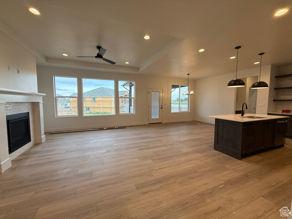 Unfurnished living room featuring a sink, light wood-type flooring, a fireplace, recessed lighting, and ceiling fan