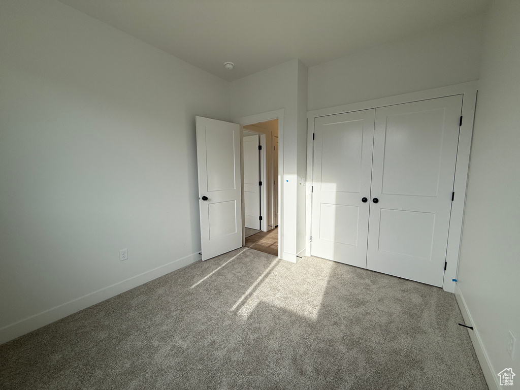 Unfurnished bedroom featuring carpet floors, baseboards, and a closet
