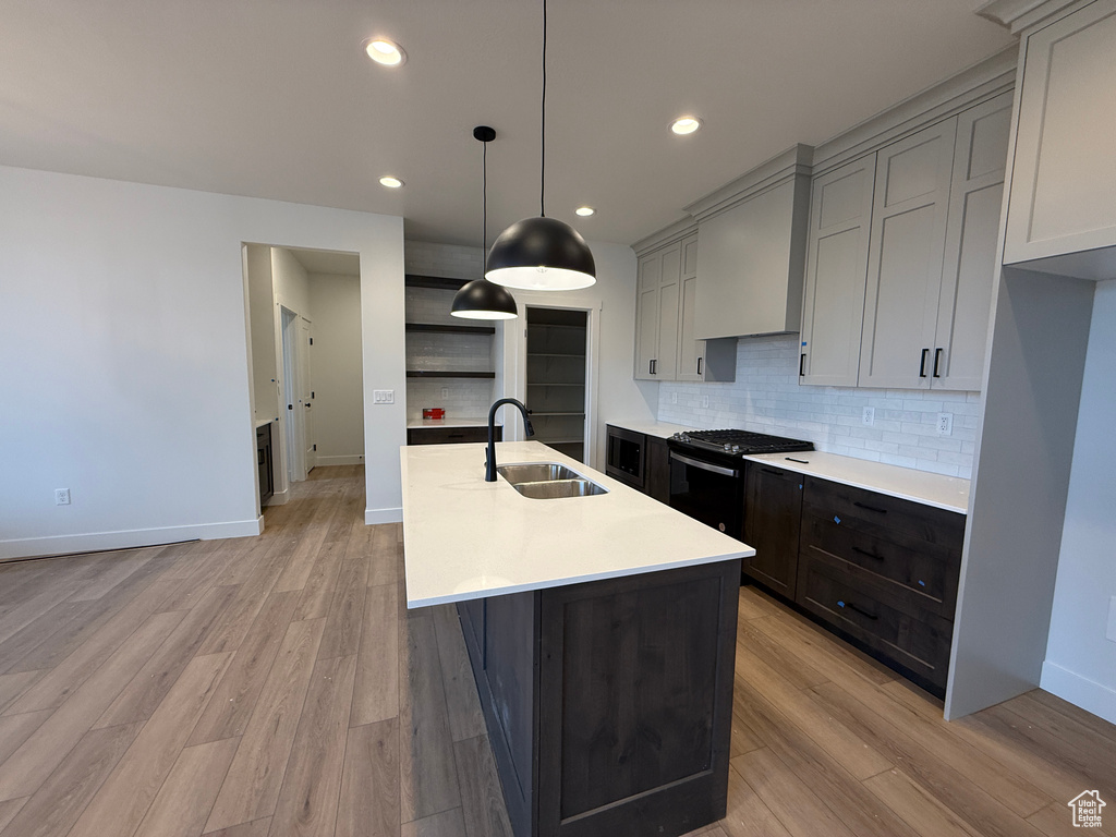 Kitchen featuring a sink, light countertops, light wood-style floors, black gas stove, and recessed lighting
