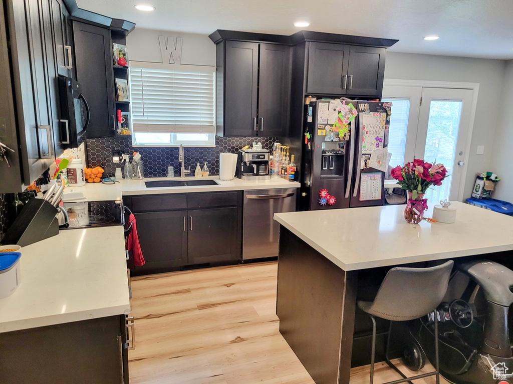 Kitchen featuring appliances with stainless steel finishes, a sink, plenty of natural light, light wood finished floors, and recessed lighting