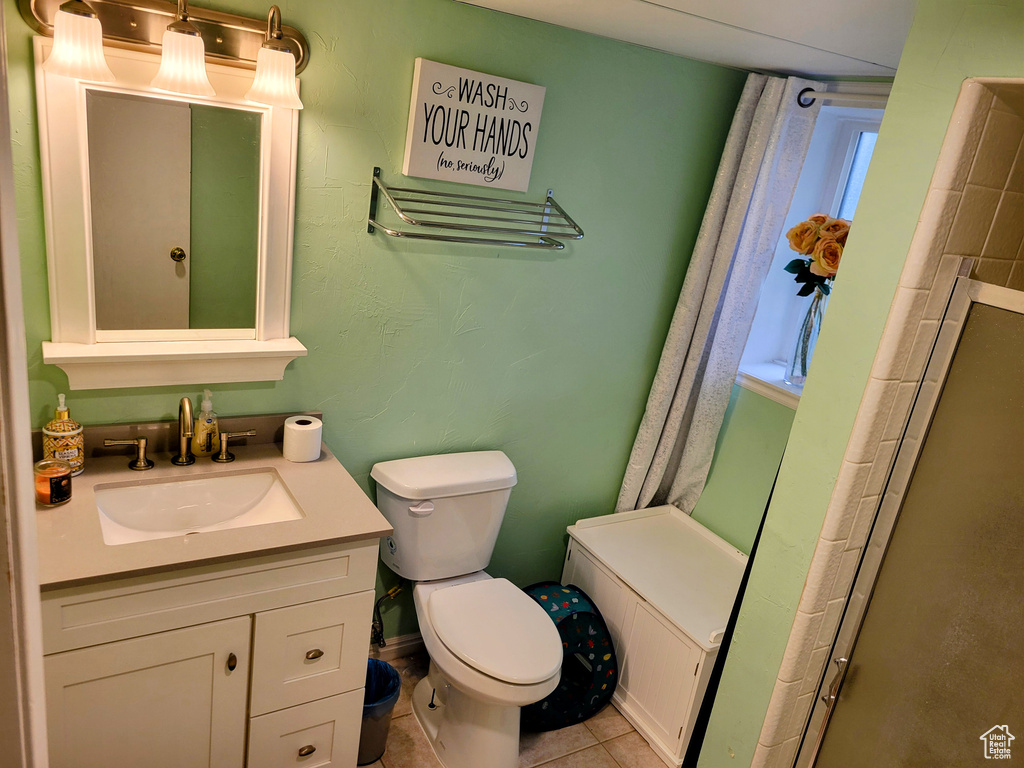 Full bathroom featuring toilet, vanity, tile patterned floors, and a shower