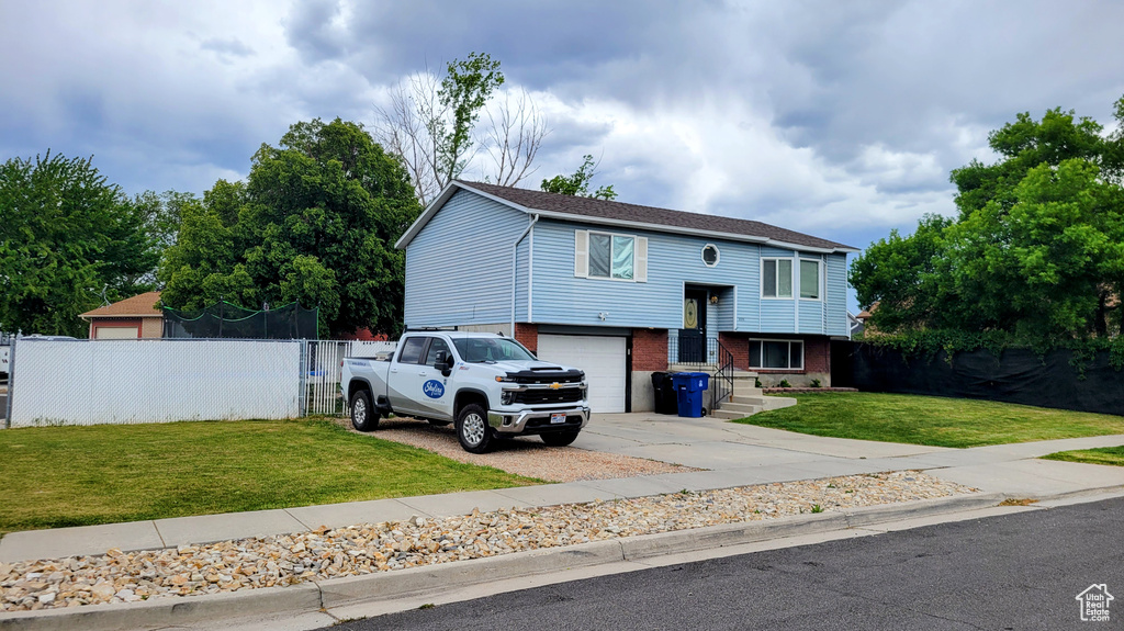 Split foyer home featuring brick siding, concrete driveway, and a garage