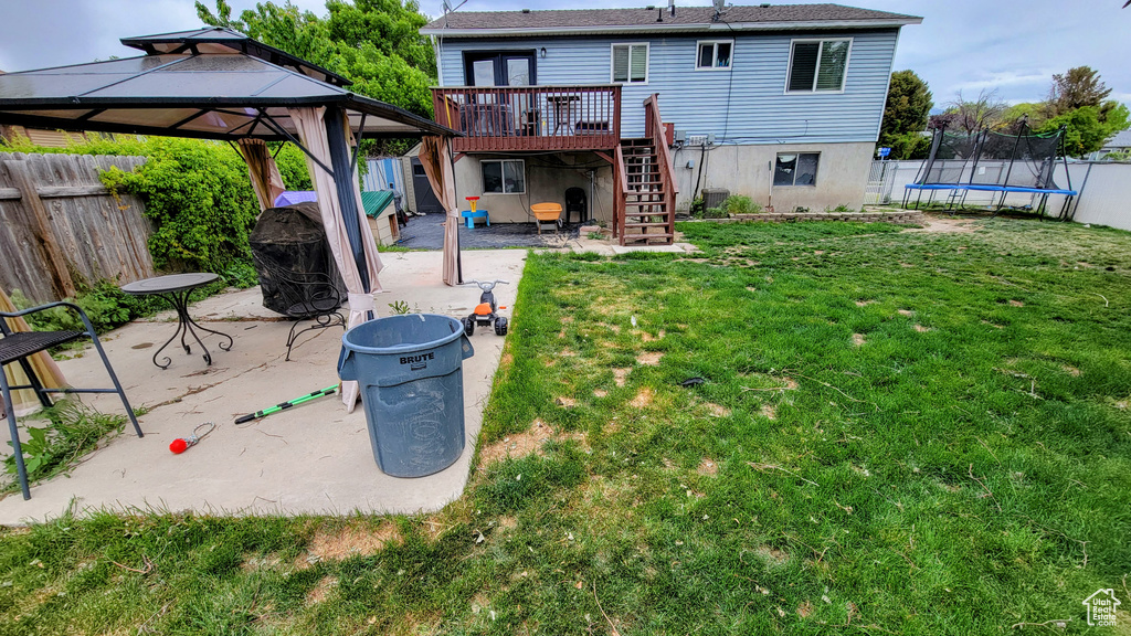 Rear view of house with a trampoline, stairs, a wooden deck, a patio, and a gazebo