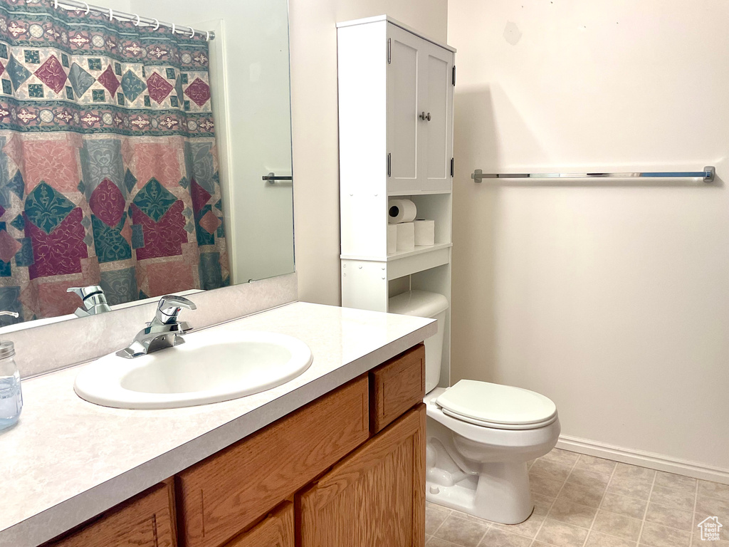 Bathroom featuring toilet, vanity, baseboards, and a shower with curtain
