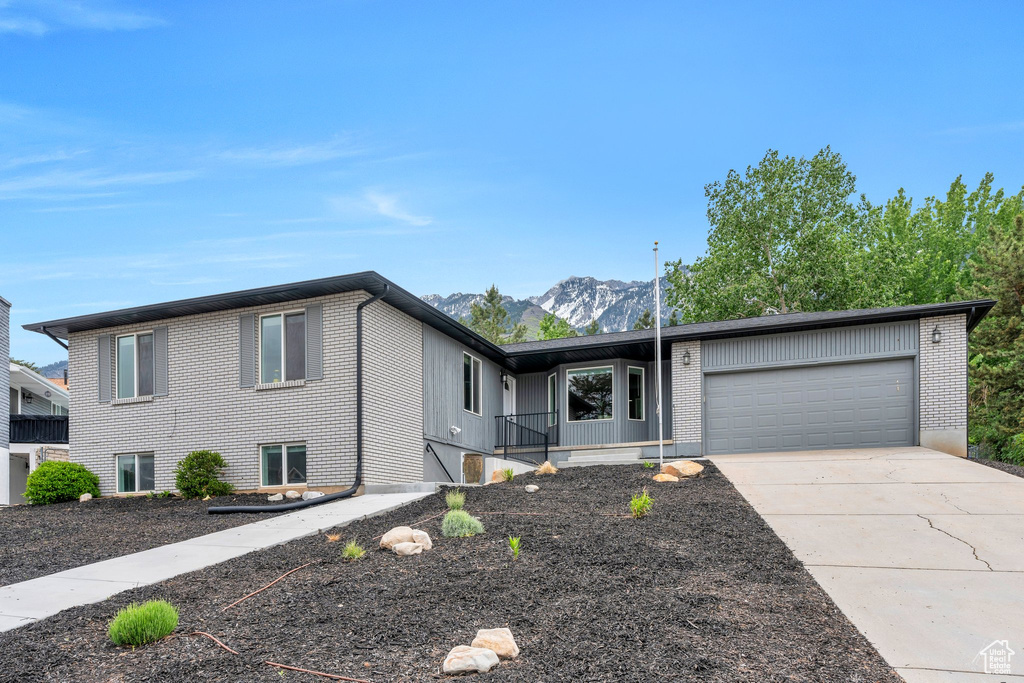 View of front of property with brick siding, an attached garage, concrete driveway, and a mountain view