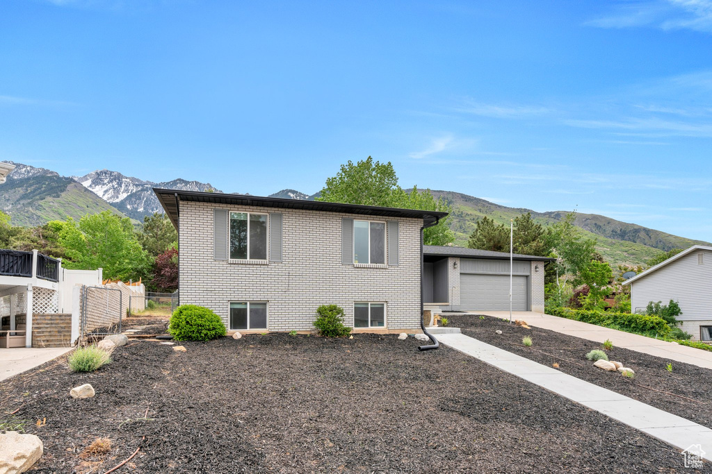Split level home with a mountain view, brick siding, a garage, and concrete driveway