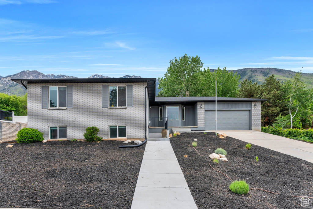 Tri-level home with brick siding, a mountain view, an attached garage, and concrete driveway