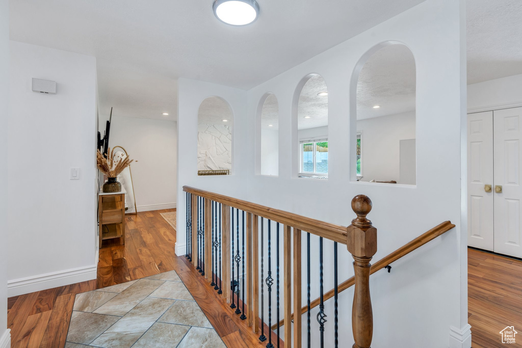 Hall with baseboards, wood finished floors, and an upstairs landing