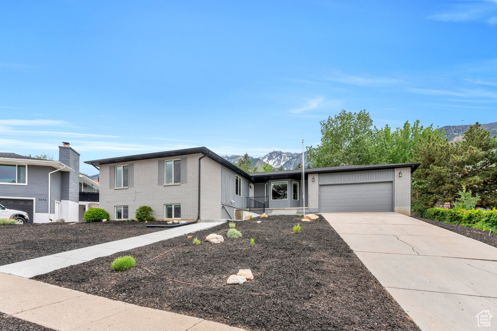 View of front facade with a garage, a mountain view, brick siding, and driveway