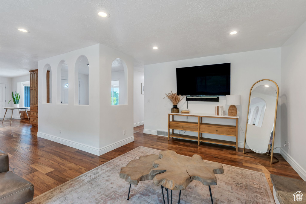 Living room featuring baseboards, wood finished floors, healthy amount of natural light, and recessed lighting