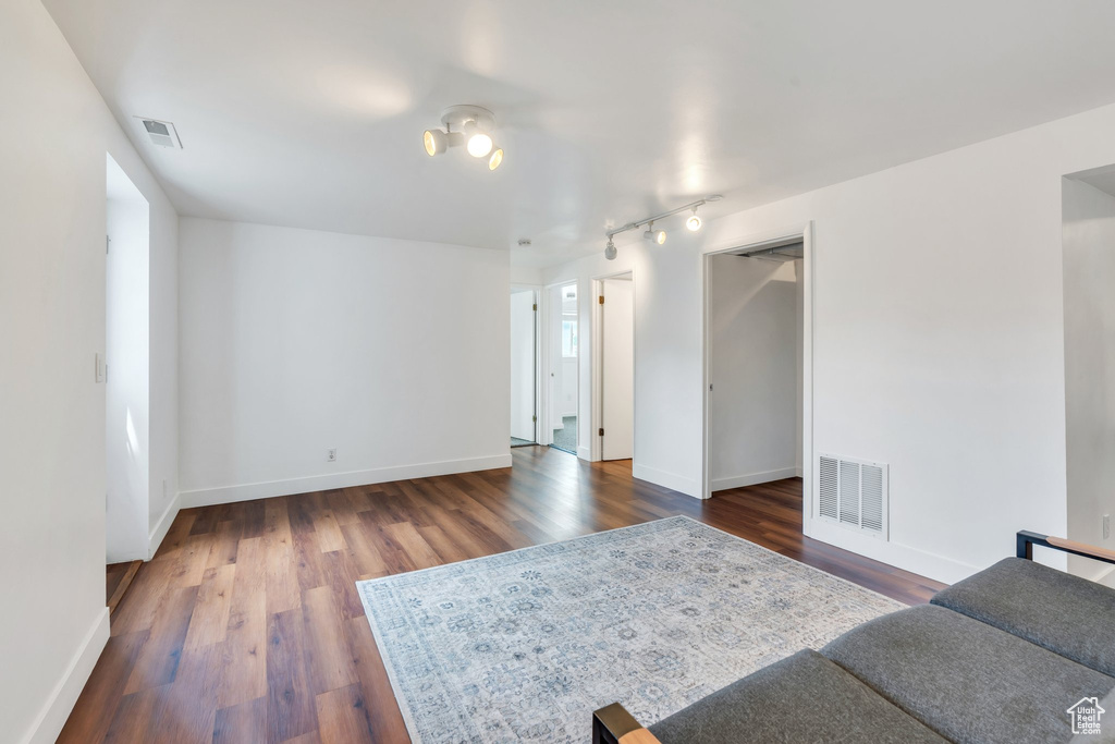 Living room with dark wood-style floors, baseboards, and rail lighting