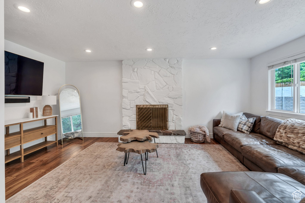 Living area featuring wood finished floors, recessed lighting, a textured ceiling, baseboards, and a fireplace