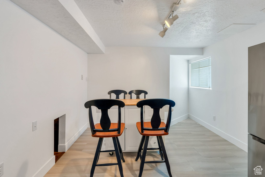 Dining room featuring baseboards, rail lighting, and a textured ceiling
