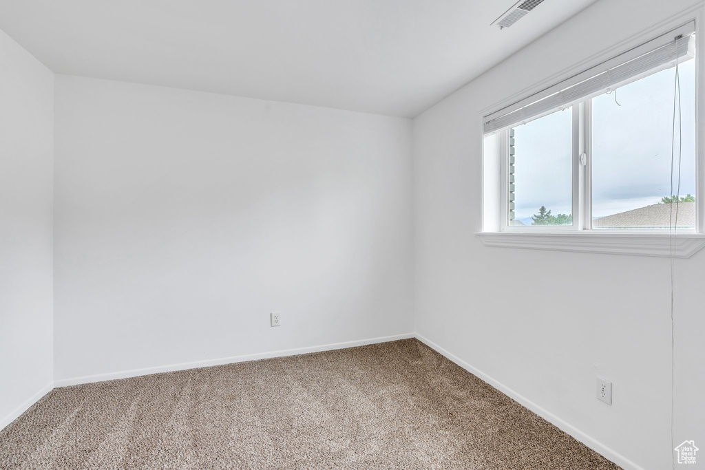 Carpeted spare room featuring baseboards