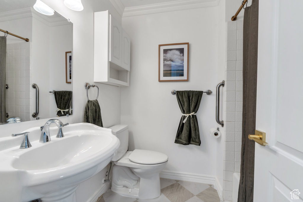 Full bath with a sink, toilet, crown molding, baseboards, and shower / washtub combination