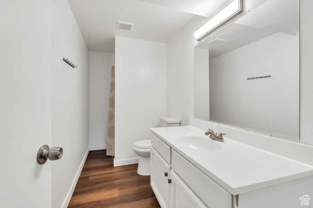 Bathroom featuring baseboards, wood finished floors, toilet, and vanity
