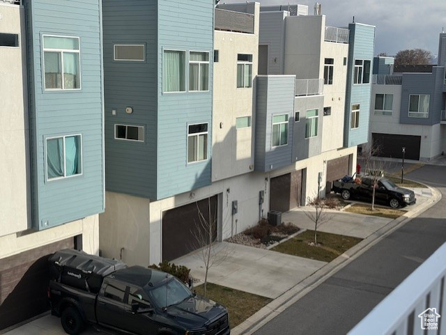 View of property featuring a garage, cooling unit, and concrete driveway
