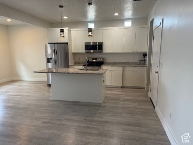 Kitchen with stainless steel appliances, a sink, baseboards, white cabinetry, and light wood finished floors