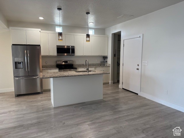 Kitchen with stainless steel appliances, a sink, white cabinetry, light wood-style flooring, and a textured ceiling