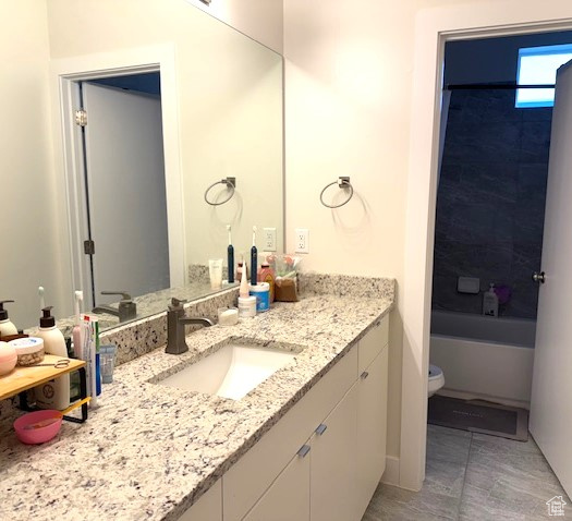 Bathroom featuring vanity, toilet,  shower combination, and tile patterned flooring