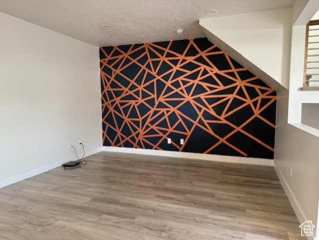 Spare room featuring wood finished floors, baseboards, and a textured ceiling
