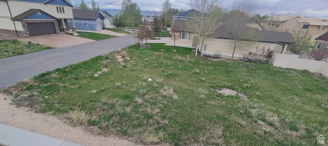 View of grassy yard with a residential view and concrete driveway