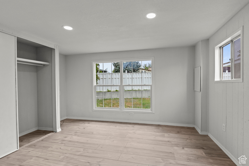 Unfurnished bedroom with multiple windows, light wood-type flooring, recessed lighting, and baseboards