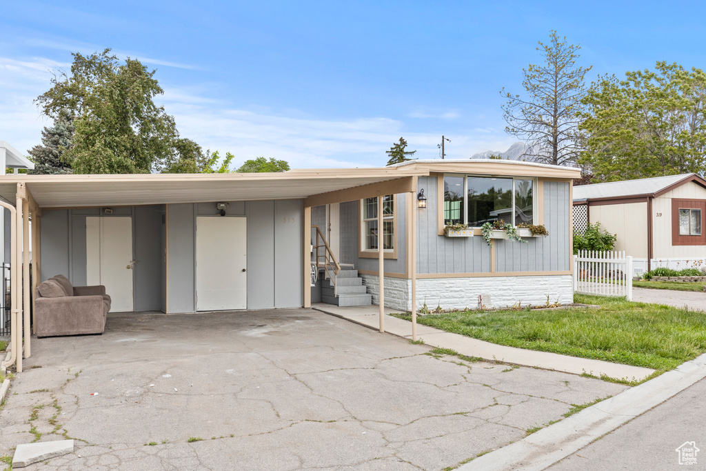 Manufactured / mobile home featuring a carport, driveway, and fence