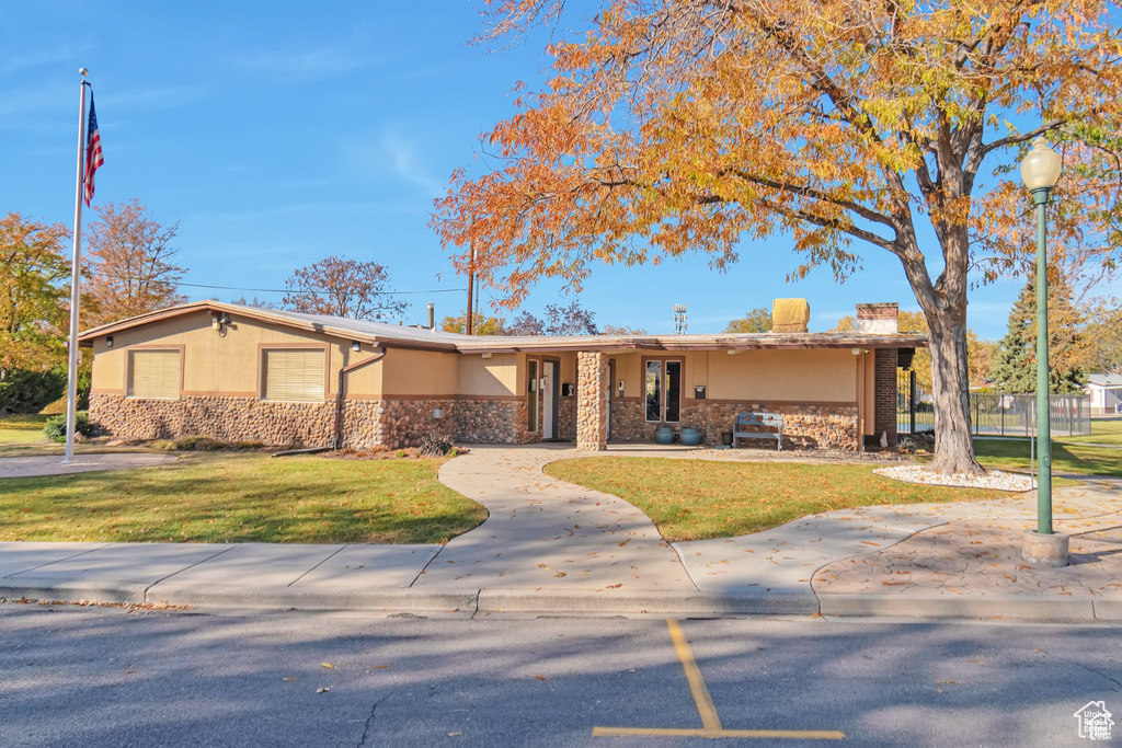 Ranch-style home with stucco siding, stone siding, and a front yard