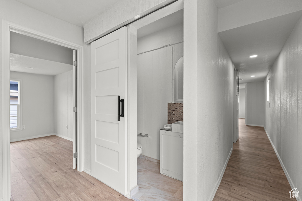 Hall with light wood-style floors, baseboards, and recessed lighting