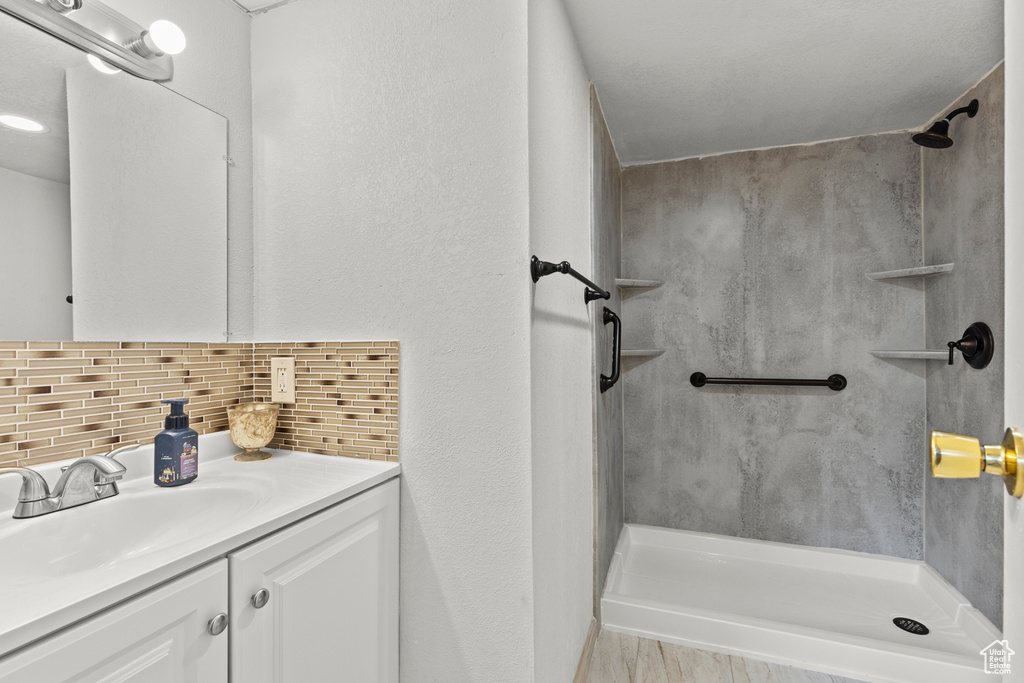 Bathroom with a walk in shower, decorative backsplash, and vanity