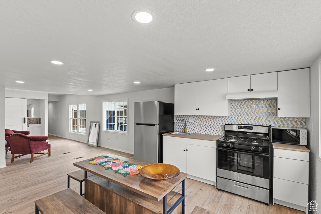 Kitchen featuring appliances with stainless steel finishes, recessed lighting, tasteful backsplash, white cabinetry, and under cabinet range hood