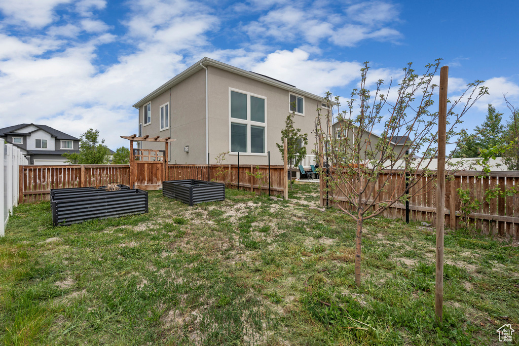 Back of house with a vegetable garden and stucco siding