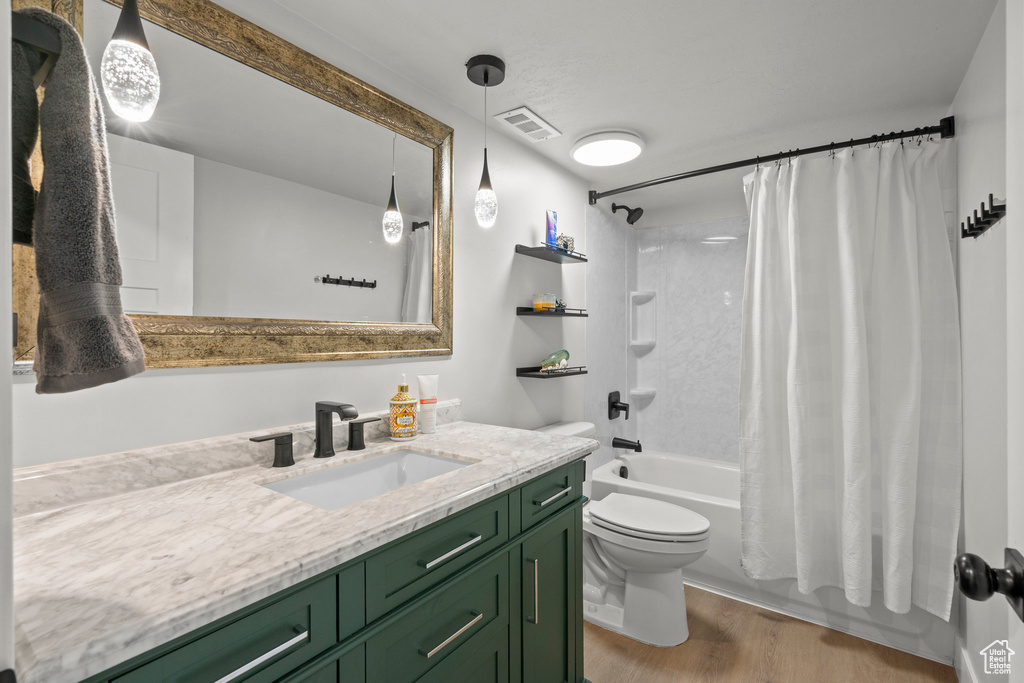 Full bathroom featuring shower / bath combo with shower curtain, wood finished floors, toilet, and vanity