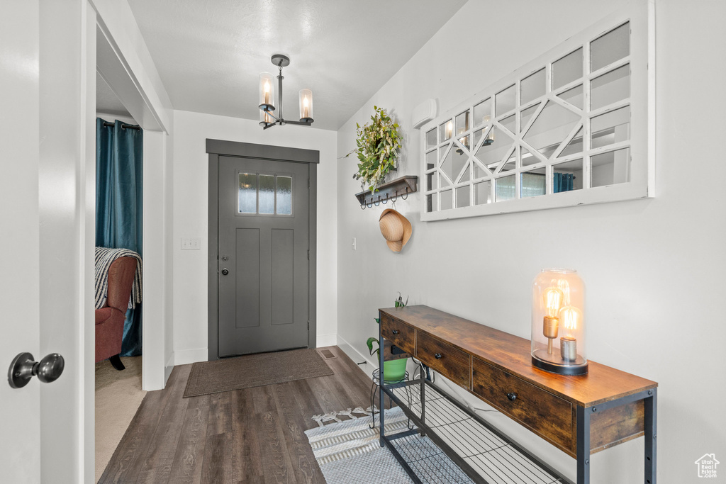 Foyer featuring baseboards, wood finished floors, and a chandelier