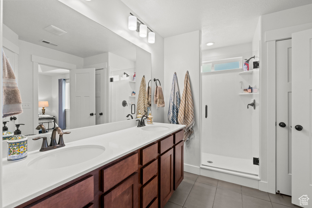 Bathroom with a stall shower, tile patterned flooring, and double vanity