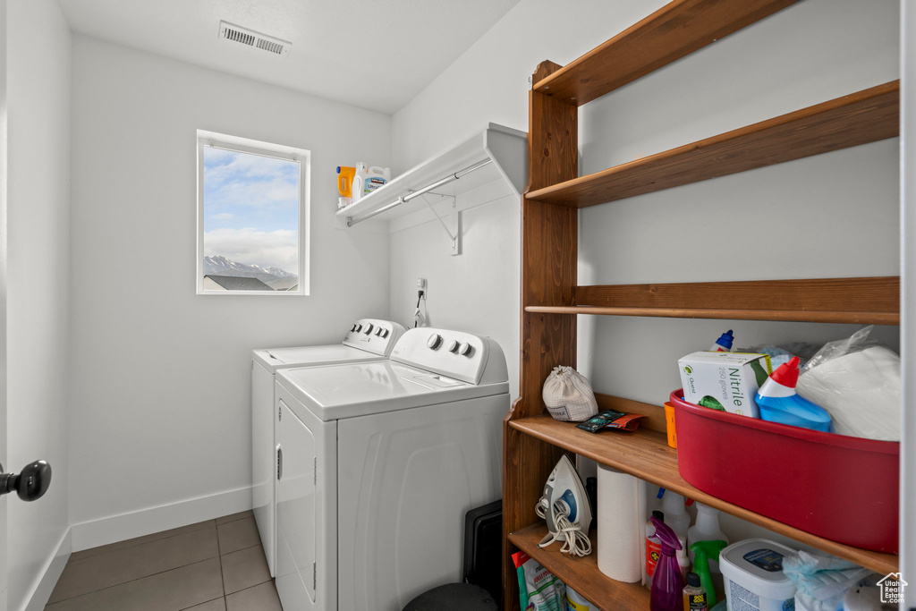 Clothes washing area with washer and clothes dryer, light tile patterned floors, and baseboards