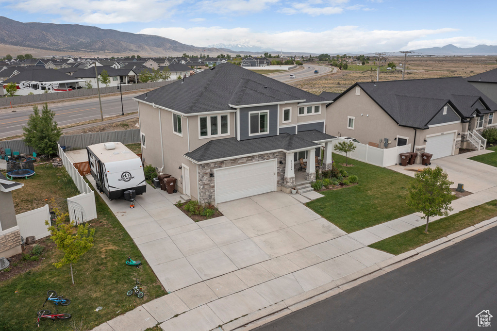 View of front of home featuring concrete driveway, a residential view, a mountain view, and a shingled roof