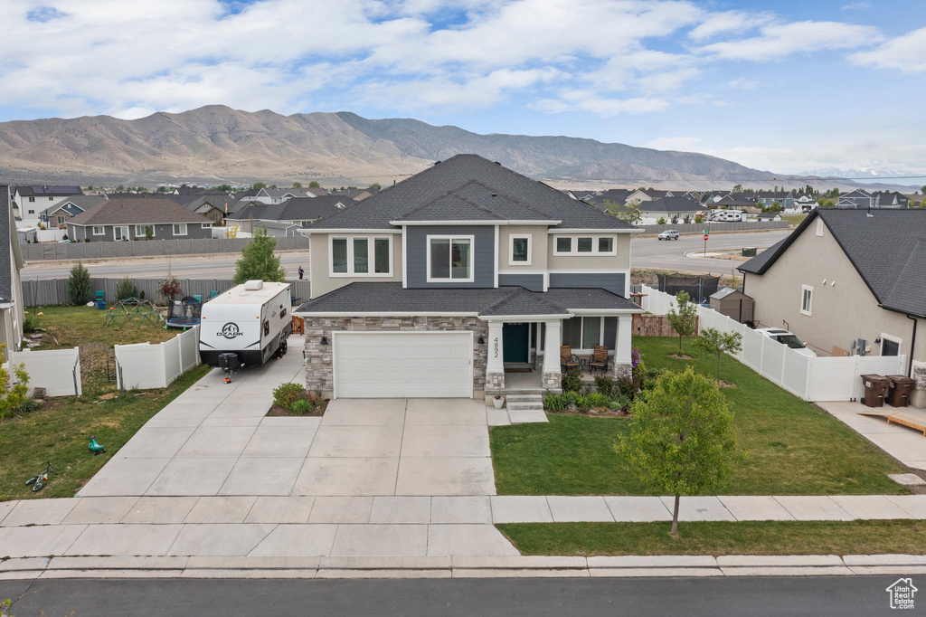 View of front of property featuring a mountain view, a residential view, driveway, a garage, and stone siding