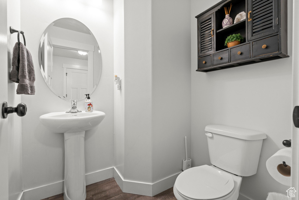 Bathroom featuring baseboards, toilet, and wood finished floors