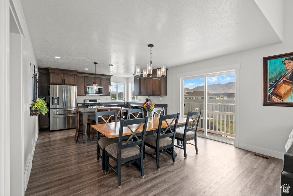 Dining room featuring dark wood-style flooring, baseboards, a chandelier, and recessed lighting