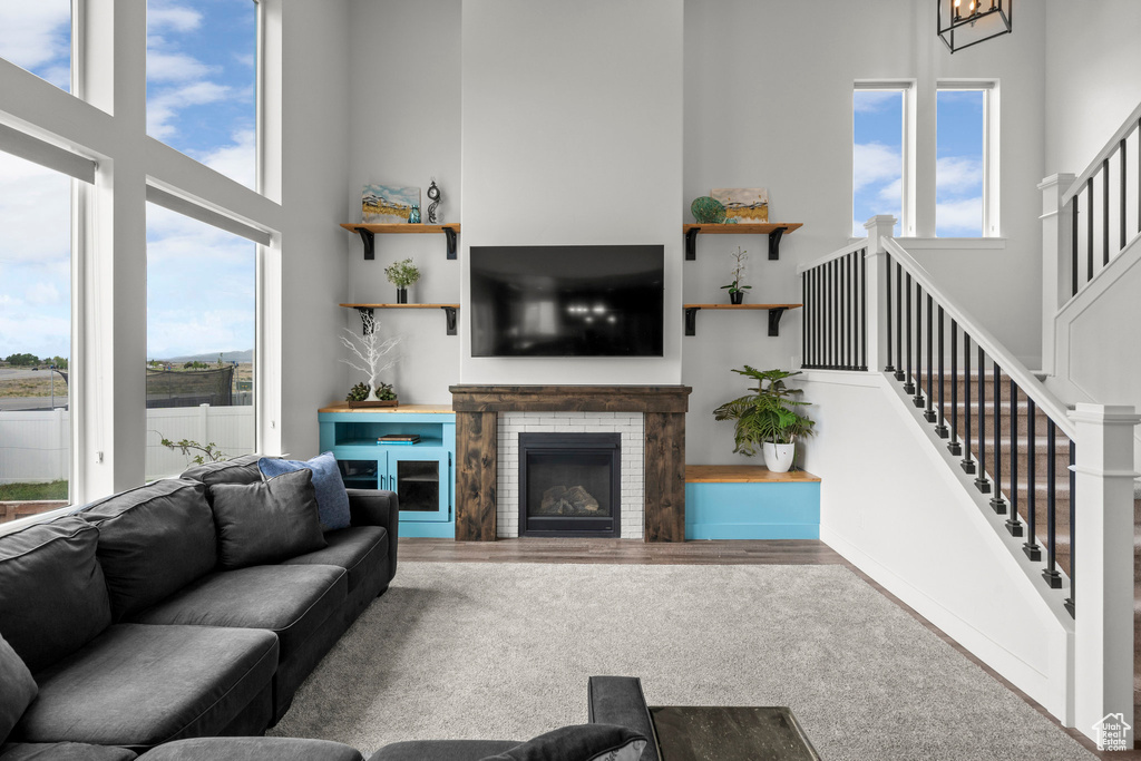 Living area with a high ceiling, stairs, wood finished floors, and a brick fireplace