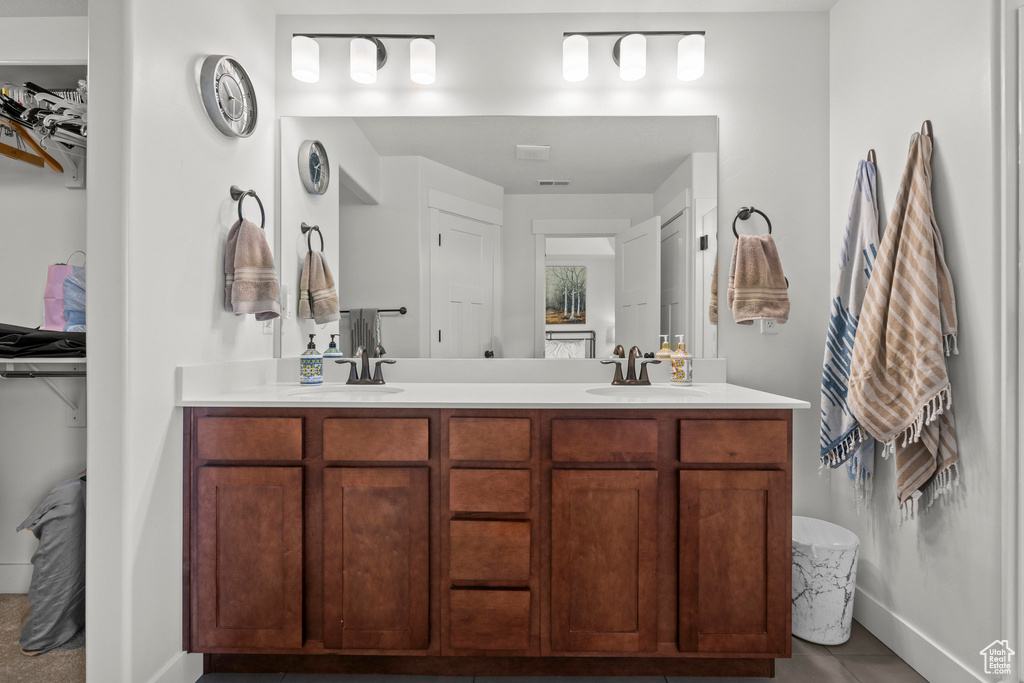 Full bathroom featuring double vanity, baseboards, and tile patterned floors