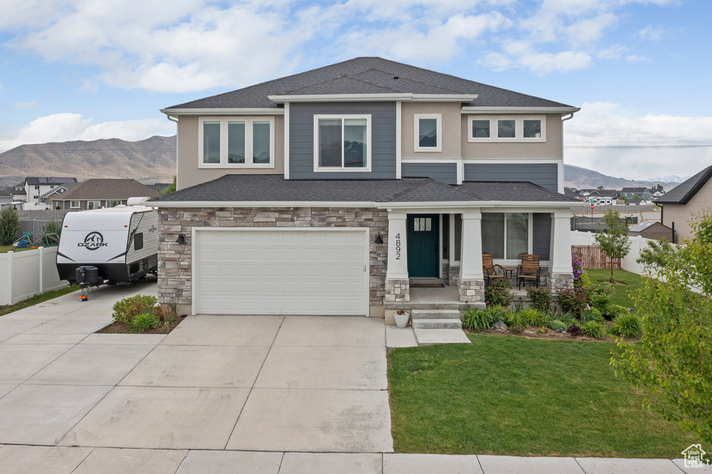 Prairie-style house featuring a mountain view, concrete driveway, an attached garage, and stone siding