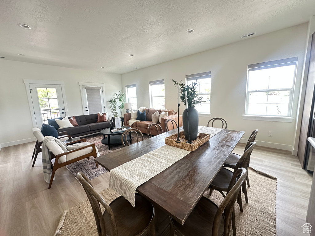 Dining area with light wood-style floors, baseboards, a textured ceiling, and recessed lighting