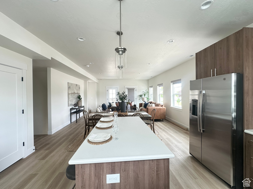 Kitchen featuring stainless steel fridge with ice dispenser, light countertops, light wood-type flooring, and recessed lighting