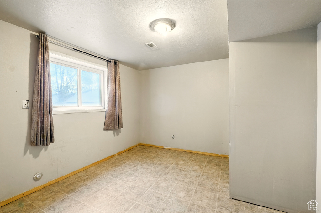 Unfurnished room featuring baseboards, a textured ceiling, and light flooring