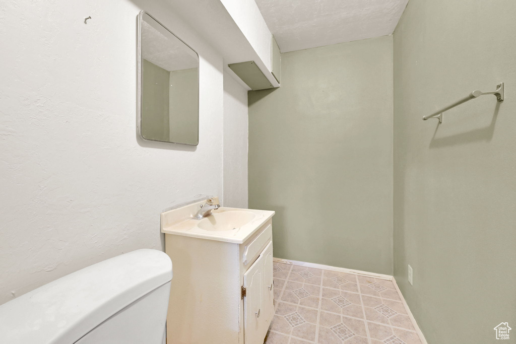Bathroom with toilet, vanity, tile patterned flooring, and baseboards