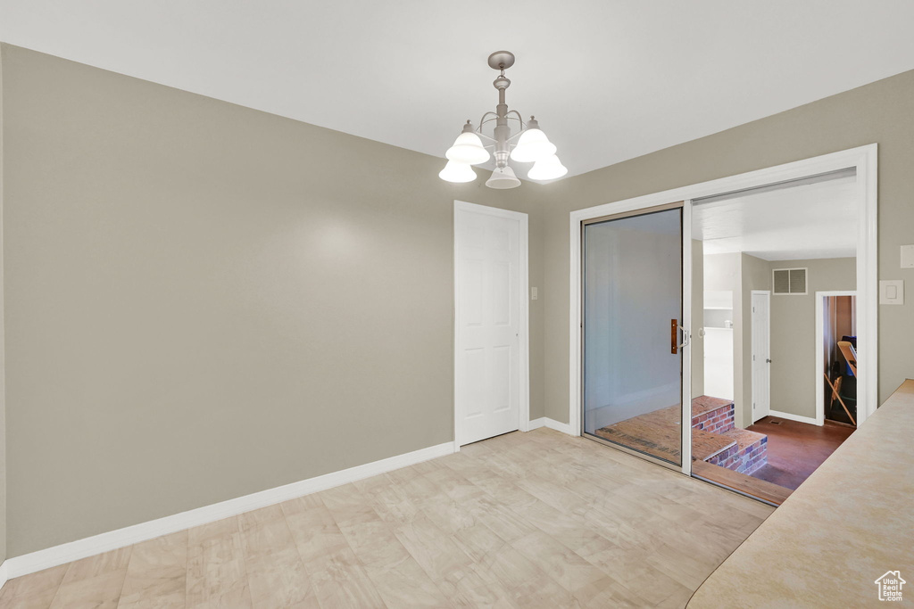 Unfurnished dining area with a chandelier and baseboards