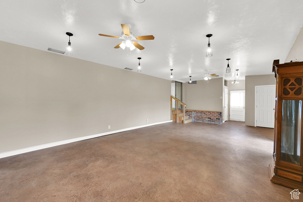 Unfurnished living room with ceiling fan, finished concrete floors, and baseboards
